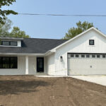 8241 Peil Ln Exterior. White Vinyl Board & Batten Siding with Black Windows & Black Painted Front Entry Door. Covered Porch. 2-Stall Garage. Carriage Hardware. Shed Style Dormer.