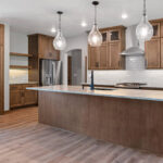 673 Black Earth Kitchen. Stained Maple Flat Panel Cabinets. Center Island. Cabinet Pantry Door. Snowfall Granite Countertops. Floating Shelves. Oasis Drift Tiled Backsplash. Downtown King Street Luxury Vinyl Plank Floors. Sherwin-Williams Anew Grey SW7030. Stainless Chimney Range Hood.