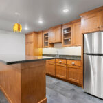 1354 Lucy Ln Basement Wet Bar with Island Countertop. Stone Countertops. Ceramic Tile Floors. Stained Maple Flat Panel Custom Cabinets.