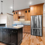 1354 Lucy Ln Kitchen with Granite Countertops, Painted Black Island, Cookbook Display Cabinet, Stained Maple Custom Cabinets, Under-Cabinet Lighting, Tiled Backsplash, Natural Maple Site Finished Hardwood Floors.