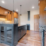 1354 Lucy Ln Kitchen with Granite Countertops, Painted Black Island, Cookbook Display Cabinet, Stained Maple Custom Cabinets, Under-Cabinet Lighting, Tiled Backsplash, Natural Maple Site Finished Hardwood Floors.
