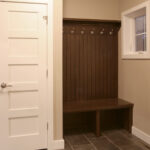 1502 Maple Hills Back Entry Bench + Coat Hooks. Stained Maple Beadboard Between Bench & Hooks. 5-Panel Flat Stacked Painted White Interior Doors. 12x24 Staggered Joint Gray Tiled Flooring.