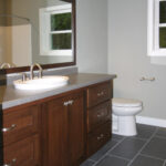 1502 Maple Hills Main Bathroom Vanity. Vessel Sink in Laminate Countertops. Wood Framed Mirror. Staggered Joint 12x24 Vinyl Tile Floors. Stained Maple Flat Panel Vanity Cabinet.