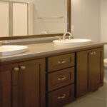 1502 Maple Hills Owner's Bathroom Vanity. Vessel Sinks in Laminate Countertops. Wood Framed Mirror. Staggered Joint Vinyl Tile Floors. Stained Maple Flat Panel Vanity Cabinet.