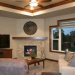 395 Whispering Creek Great Room + Fireplace. 12" Deep Stepped Tray Ceiling with Crown Molding. Stacked Stone Fireplace to Mantel Height with Stained Maple Boxed Beam Style Mantel.