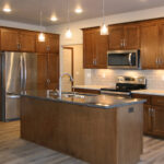 514 Rosemary Kitchen. Stained Maple Flat Panel Custom Cabinets. Granite Countertops. Subway Tile Backsplash. Under-Cabinet Lighting. Luxury Vinyl Plank Floors.