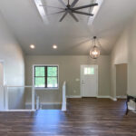 7714 Saint Andrews Foyer + Stairs. Cable Railing with Wood Posts + Rail. Luxury Vinyl Plank Floors. U-Shaped Stairs. Cathedral Ceiling with Painted Wood Beams.
