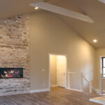 7714 Saint Andrews Great Room + Stacked Stone Linear Fireplace. Cable Railing with Painted Wood Posts + Railing. Luxury Vinyl Plank Floors. Cathedral Ceiling with Painted Wood Beams.