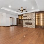 7736 Turnberry Great Room + Foyer + Fireplace + Built-Ins. Modern Stacked Stone Linear Fireplace. Steel Mantels. Obscure Glass Doors. Modern Walnut Front Entry Door. Luxury Vinyl Plank.