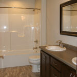 5012 Potters Crossing 2nd Floor Bathroom. 12x24 Tile Staggered Joint Pattern. Fiberglass Shower Module with Curved Shower Rod. Stained Maple Flat Panel Custom Cabinet Vanity.