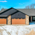 311 S Splake Exterior. Black Vertical Board + Batten Siding. Woodgrained Overhead Garage Doors.