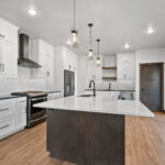 311 S Splake Kitchen. Painted Perimeter Cabinets + Stained Island. Floating Shelves. Tiled Backsplash. Stone Countertops. Chimney Hood over Slide-In Range.