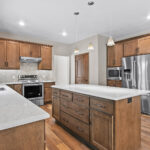 3597 E Hank Kitchen. Stone Countertops. Stained Maple Custom Cabinets. Under-Cabinet Range Hood. Built-In Microwave with Trim Kit. Herringbone Pattern Tiled Backsplash. Luxury Vinyl Plank Floors.