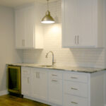 2411 Pristine Wet Bar. Under-Counter Refrigerator. White Subway Tile Backsplash. Pendant Light over Bar Sink. White Painted Flat Panel Cabinets.