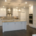 2411 Pristine Kitchen. White Painted Custom Flat Panel Cabinets. Under-Counter Refrigerator. Subway Tile Backsplash. Double Wall Oven. Chimney Range Hood over Cooktop. Granite Countertops. Glass Doors with Lights.