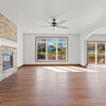 3320 Cottage Hill Living Room + Fireplace. Floor-To-Ceiling Stone Fireplace Surround with Painted White Mantel. Archway. Luxury Vinyl Plank Floors.
