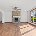 3320 Cottage Hill Living Room + Fireplace. Floor-To-Ceiling Stone Fireplace Surround with Painted White Mantel. Archway. Luxury Vinyl Plank Floors.