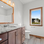 3320 Cottage Hill Main Bathroom. Stained Maple Vanity Cabinet with Granite Countertops & Wood Framed Mirror. Grouted Vinyl Tile Flooring.
