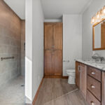 3320 Cottage Hill Owners Bathroom. Walk-In Tiled Shower Barrier Free Zero Entry. Stained Maple Vanity Cabinet with Granite Countertops & Wood Framed Mirror. Slip-In Linen Cabinet. Luxury Vinyl Plank Floors.