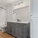 704 Royal St Pats 2nd Floor Bathroom. Painted Gray Bathroom Vanity Cabinet with White Quartz Countertops. Wood Framed Mirror.