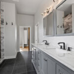 704 Royal St Pats Owners Bathroom. Painted Gray Vanity with White Stone Countertops. Walk-In Tiled Shower. Grouted Vinyl Tile Flooring.