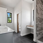 704 Royal St Pats Owners Bathroom. Painted Gray Vanity with White Stone Countertops. Walk-In Tiled Shower. Makeup Vanity with Wood Top. Grouted Vinyl Tile Flooring.