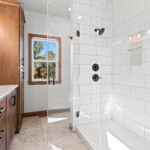 2960 Park Rd Owners Bathroom + Tiled Shower. Shampoo Niches with Glass Shelves. Foot Niche. Heavy Glass Shower Enclsoure. Fiberglass Shower Base with Tiled Walls. Viny Tile Floors. Quartz Countertops. Maple Vanity Cabinet with Full Corner Linen and Stained Finish.