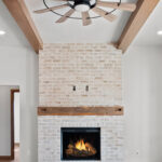 2960 Park Rd Great Room + Fireplace. Brick fireplace surround with reclaimed distressed hewn timber mantel. Luxury vinyl plank floors. Maple ceiling beams.
