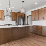 2960 Park Rd Kitchen. Stained maple cabinets, white quartz countertops, white subway tile backsplash, stainless appliances, chimney range hood, center island, slide-in range, luxury vinyl plank floors.