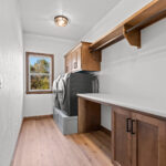 2960 Park Rd Laundry. Stained maple base cabinet open below for baskets with folding counter. Built-in laundry waser & dryer raised pedestal painted gray.