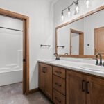 2960 Park Rd Main Bathroom. Stained maple vanity cabinet. Wood-framed mirror. Vinyl tile flooring.