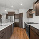 116 Cortland Kitchen. Stained Maple Cabinets. Center Island. Stainless Steel Appliances. Chimney Range Hood. Calacatta Lucia White Quartz Countertops. Luxury Vinyl Plank Floors. Corner Walk-In Pantry.
