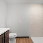 116 Cortland Owners Bathroom. Tiled Shower Walls with Shampoo Shelves & White Fiberglass Shower Base. Quartz Countertops. Stained Maple Cabinets.