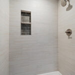 116 Cortland Owners Bathroom. Tiled Shower Walls with Shampoo Shelves & White Fiberglass Shower Base. Quartz Countertops. Stained Maple Cabinets.