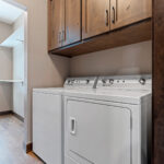 2966 Sugar Bush Laundry. Knotty Alder Stained Upper Cabinets over Washer & Dryer.