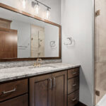 2966 Sugar Bush Main Bathroom + Tiled Shower. Stained Knotty Alder Vanity Cabinet. Fantasy Blue Leathered Granite Countertops. Knight Tile "Bern Stone" Vinyl Tile Flooring. Wood Framed Mirror. Heavy Glass Shower Enclosure. Angora Ameila Smoke shower wall tile.