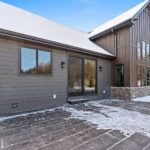 2966 Sugar Bush Exterior with Stamped & Colored Patio. LP SmartSide Diamond Kote "DuoBlend Bedrock" vertical board & batten siding with "DuoBlend Elkhorn" horizontal clapboard lap siding and "Coffee" trim. Eldorado "Mountain Ledge Silverton" stone. Gilpin's Falls Bridge Plank Pattern with U18 Gull Gray Base Color & R13 Deep Charcoal Release Color.