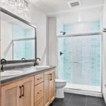 525 E Greenfield 2nd Floor Bathroom. Vinyl Tile Floors. Light Stain Maple Vanity Cabinet. Tiled Shower. Wood Framed Mirror. Semi-Frameless Gliding Shower Door.