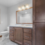 526 Rosemary Owners Bathroom. Stained maple custom vanity and linen cabinets Wood mirror frames. Luxury vinyl tile floors.