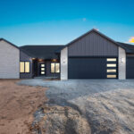 398 Red Tail Exterior. Mid-Century Modern Revival. Flush Panel Overhead Garage Doors with Vertically Stacked Windows. Board & Batten Vinyl Siding. Stacked Stone.