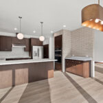 398 Red Tail Kitchen & Dining. Mid-Century Modern Revival. Interior Brick Walls. Flush Slab-Front Stained Maple Cabinets. Floating Shelves. Built-In Wall Oven. Electric Cooktop. Under-Cabinet Range Hood. Luxury Vinyl Plank Floors.