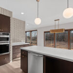 398 Red Tail Kitchen. Mid-Century Modern Revival. Interior Brick Walls. Flush Slab-Front Stained Maple Cabinets. Built-In Wall Oven. Luxury Vinyl Plank Floors.