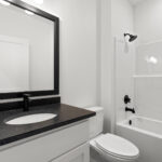 7730 Prestwick Main Bathroom. Black Granite Countertops. White Painted Woodwork Bathroom Vanity. Black Wood Mirror Frame.