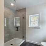 7730 Prestwick Owners Tiled Shower. Tiled Walls with White Fiberglass Shower Base. Heavy Glass Shower Enclosure. Grouted Vinyl Tile Floors. White Painted Woodwork.