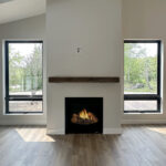 8241 Peil Ln Fireplace. Plastered Drywalled Fireplace Surround with Beam Style Mantel. Luxury Vinyl Plank Floors. Black windows with plastered drywalled returns.