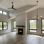 8241 Peil Ln Fireplace + Living Room. Plastered Drywalled Fireplace Surround with Beam Style Mantel. Luxury Vinyl Plank Floors. Black windows with plastered drywalled returns. Active Dormer Cathedral Ceiling.
