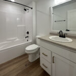 8241 Peil Ln Main Bathroom. White Painted Vanity Cabinet with Gold Hardware and Laminate Countertops. Luxury Vinyl Plank Floors. Fiberglass tub/shower module with curved shower curtain rod.