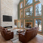 14421 N Paya Lake Rd Great Room & Fireplace. 2-Story with Cathedral Ceiling. Andersen 400 Series window wall. Sherwin-Williams SW9130 "Evergreen Fog" accent wall color. Sconce lights flanking windows. Heat & Glo Mezzo linear 60" gas fireplace. Arctic Golden splitface natural stacked stone fireplace surround.