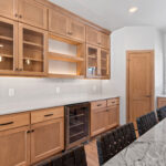 14421 N Paya Lake Rd Kitchen. Horizon Glossy "Mist" tiled backsplash to ceiling. Cortec Pro "Brookfield Maple" vinyl plank floors. Cascade granite and Silestone "Miami Vena" countertops. Corner Walk-In Pantry. Glacier White painted island with stained flat panel maple perimeter cabinets with floating shelves and glass doors. Microwave in corner cabinet. GE black slate appliances. Slide-in gas range. Under-counter beverage refrigerator.