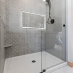 14421 N Paya Lake Rd Owners Bathroom Tiled Shower. Pathways "Arcade" and Angora Belgian Linen "Mist" tile. Alumax PL-70 sliding glass shower enclosure. Adura Flex "Vienna Alabaster" vinyl tile floors.